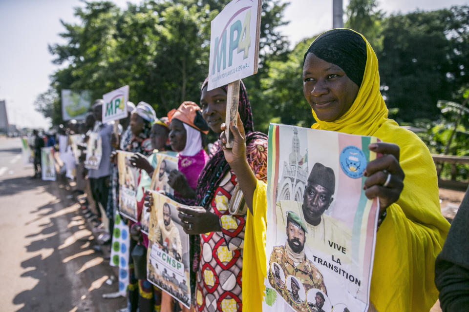 Supporters hold placards showing former Defense Minister and retired Col. Maj. Bah N'Daw, above, who is now transitional president, and Col. Assimi Goita, below, head of the junta that staged the Aug. 18 coup and who is now transitional vice president, outside a swearing-in ceremony in the capital Bamako, Mali, Friday, Sept. 25, 2020. Mali's transitional president and vice president were sworn into office Friday, more than a month after a coup in the West African nation, as Mali remains under sanctions by the 15-nation West African regional bloc ECOWAS, and amid uncertainty about details of the transition period. (AP Photo)