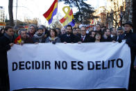 The president of Catalonian Parliament, Roger Torrent, center, and the Catalan regional President Quim Torra, center right, hold a placard that reads in Spanish: " To Choose is not a Crime", outside the Spanish Supreme Court in Madrid, Tuesday, Feb. 12, 2019. Spain is bracing for the nation's most sensitive trial in four decades of democracy this week, with a dozen Catalan separatists facing charges including rebellion over a failed secession bid in 2017. (AP Photo/Andrea Comas)