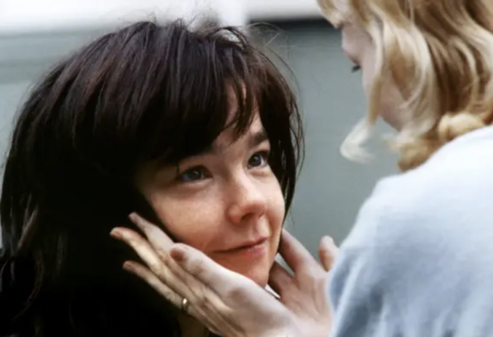 A woman cradles a smiling Bjork's face