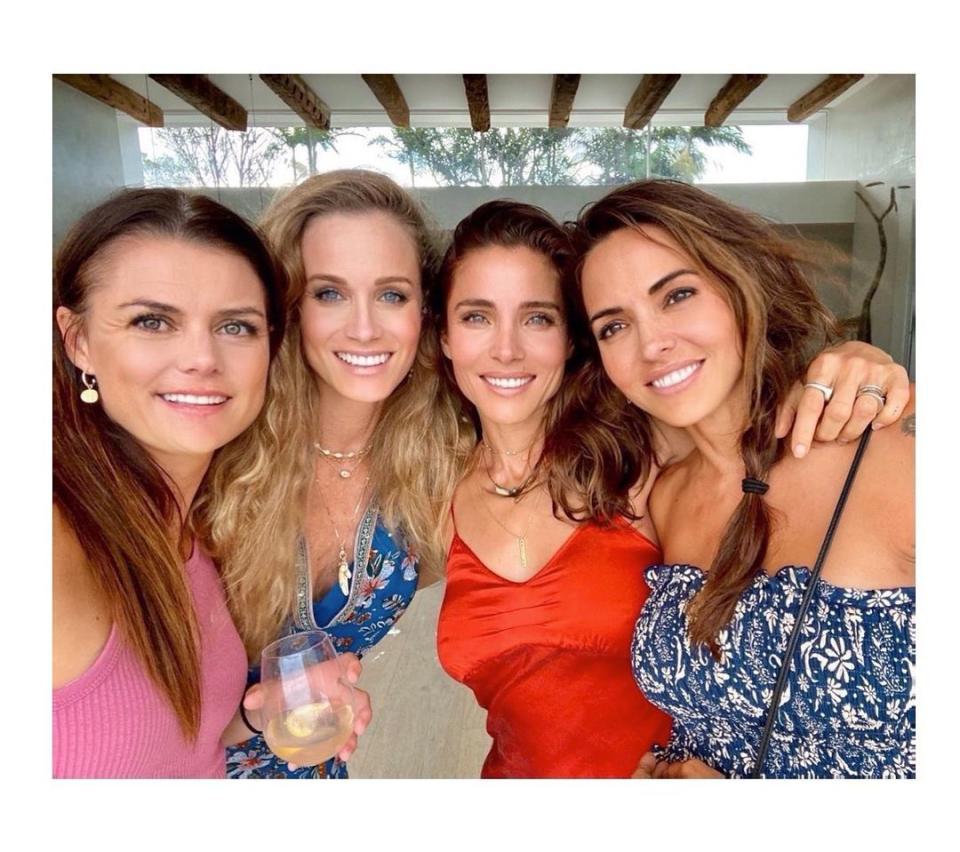 Elsa Pataky in a red top and brunette hair posing with friends