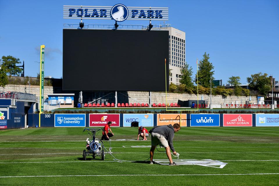 Workers paint yard lines and school names Thursday as they get Polar Park ready for football this weekend.