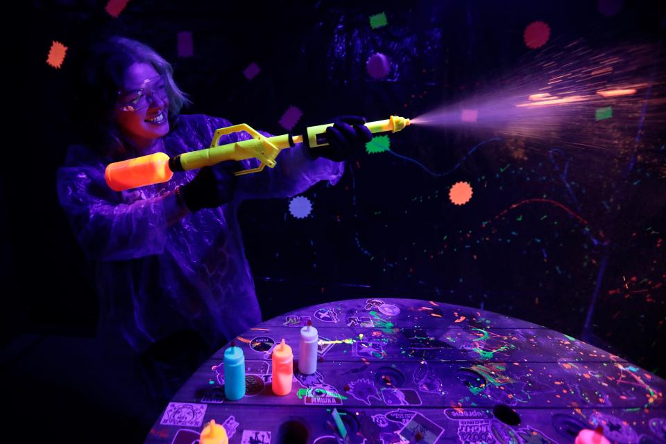 Katarina Cidade uses a paint gun to create a work of art in the glow in the dark room at the newly opened House of Rage at 832 State Road in Dartmouth.