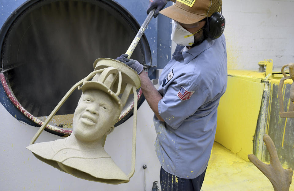 Jesse Justus, an employee at Art Castings of Colorado, touches up a wax mold of Jackie Robinson's head in Loveland, Colo. on Wednesday, May 8, 2024. The original statue was cut off at the ankles and stolen from a park in Wichita, Kansas in January. The Colorado foundry cast that sculpture in 2019 and, luckily, still had the original plaster and rubber molds. (AP Photo/Thomas Peipert)