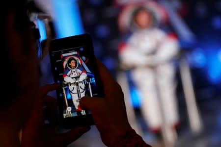 A visitors takes a picture of Advanced Space Suit Engineer at NASA Kristine Davis as she wears the xEMU prototype space suit for the next astronaut to the moon by 2024, during its presentation at NASA headquarters in Washington