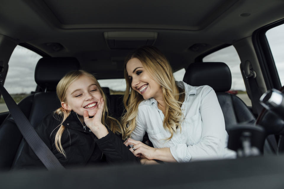 A mother and a daughter are laughing together in the car