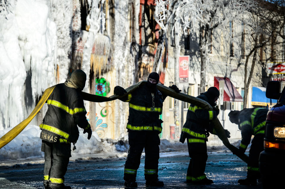 Firefighters worked to remove frozen hoses from the scene on Thursday, Jan. 2, 2014, in Minneapolis, after Wednesday's fire destroyed an apartment building. Fourteen were injured and the cause of the fire is still unclear. (AP Photo/The Star Tribune, Glen Stubbe) MANDATORY CREDIT; ST. PAUL PIONEER PRESS OUT; MAGS OUT; TWIN CITIES TV OUT