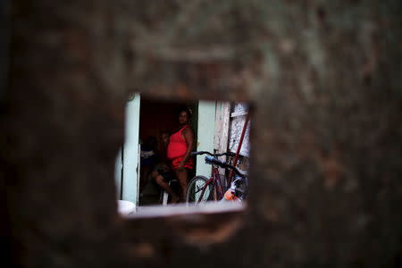 A family is seen framed by a gap in a wall inside of their stilt house, a lake dwelling also known as palafitte or 'Palafito', in Recife, Brazil, February 8, 2016. REUTERS/Nacho Doce