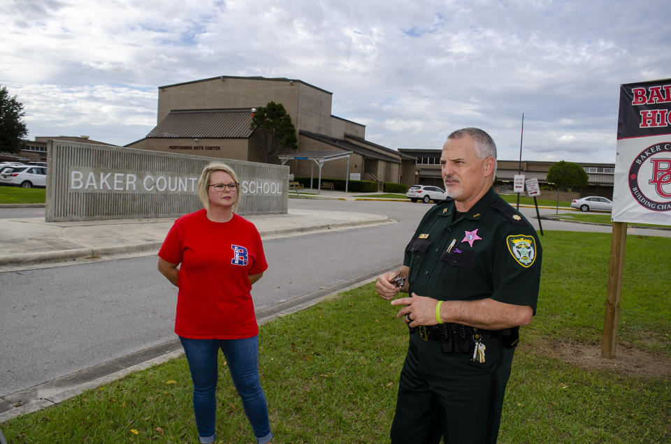 In this Oct. 16, 2019 photo, Baker County Sheriff's Maj. Randy Crews and Angela Callahan speak, outside at Baker County High School in Glen St. Mary, Fla., They share concern about a judge's decision to dismiss second-degree felony charges against a 15-year-old who had written a six-plan describing a massacre at the county's only high school. Each has a child attending Baker County High School. (AP Photo/Bobby Caina Calvan)