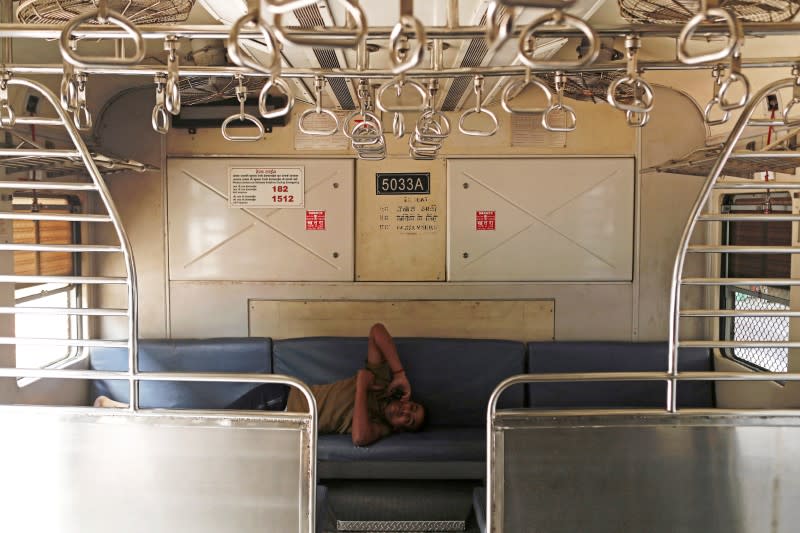 Railway employee talks on the phone inside an empty train compartment in Mumbai