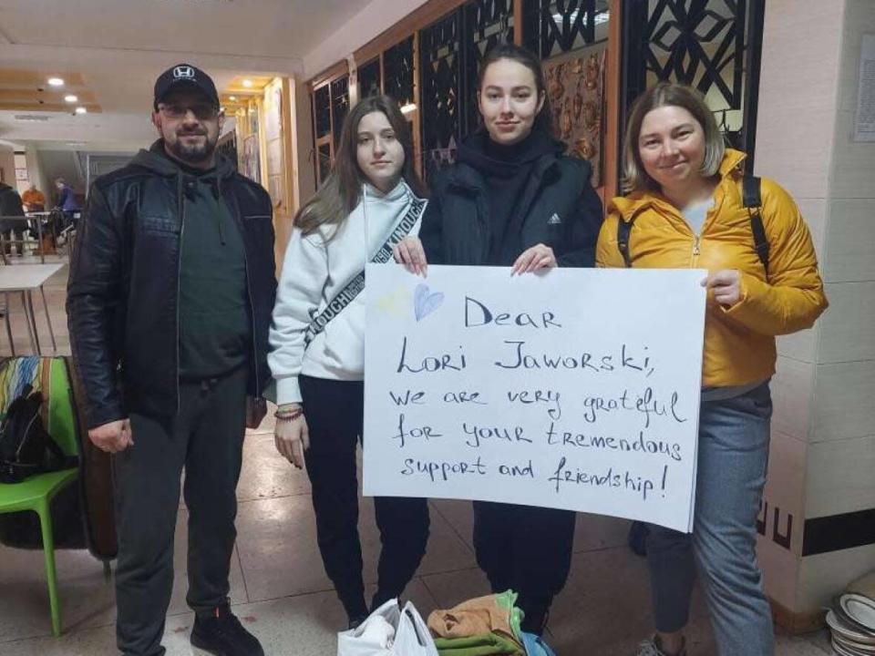 Ukrainians working with refugees in the eastern city of Dnipro hold up a sign thanking Lori Jaworski of Charlottetown for her contributions.  (Artem Pidhorniy - image credit)