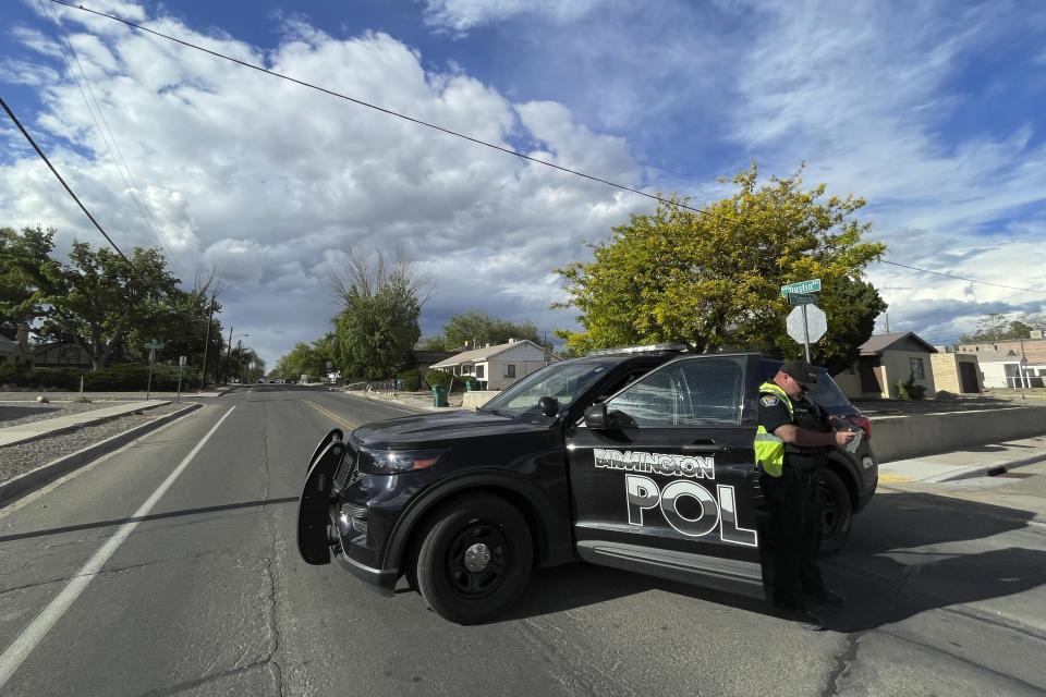 A police officer blocks traffic on a road following a deadly shooting Monday, May 15, 2023, in Farmington, New Mexico. Authorities said an 18-year-old opened fire in the northwestern New Mexico community, killing multiple people and injuring others, before law enforcement fatally shot the suspect. (AP Photo/Susan Montoya Bryan)