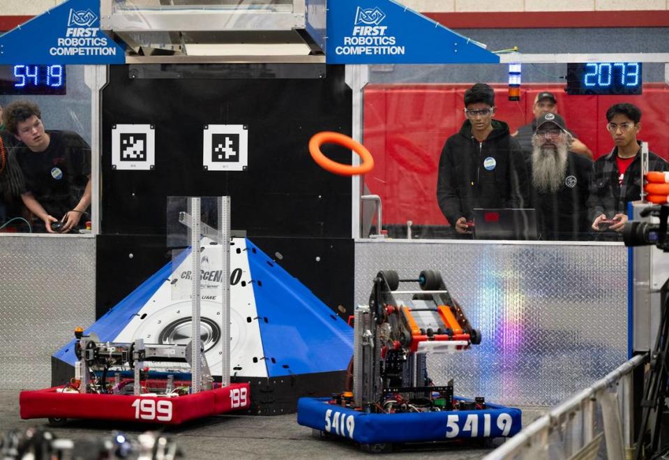 Pleasant Grove High School EagleForce’s Hurmann Saini, coach Matt Beaudin and Logan Wong compete during the FIRST Robotics Competition at their school in Elk Grove on Friday.