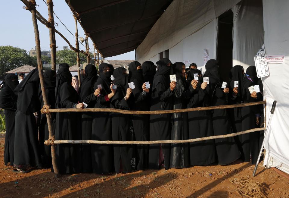 Indian Muslim women display their voters identity cards as they stand in a queue to cast their votes at a polling station in Mumbai India, Thursday, April 24, 2014. The multiphase voting across the country runs until May 12, with results for the 543-seat lower house of parliament expected on May 16. (AP Photo/Rajanish Kakade)