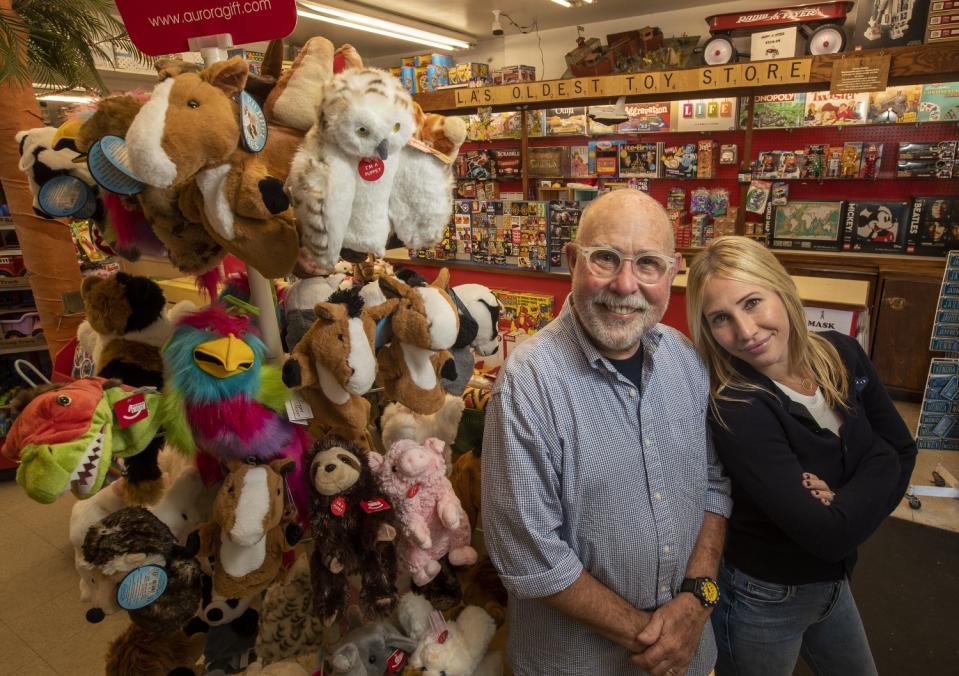 A man and a woman stand next to a toy display.