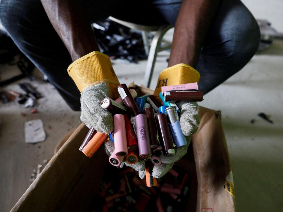 An employee holds a handful of lithium-ion cells from old laptop battery packs at a recycling facility