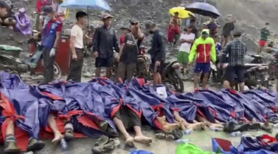 In this image made from video, people gather near the bodies of victims of a landslide near a jade mining area in Hpakant, Kachin state, northern Myanmar Thursday, July 2, 2020. Myanmar government says a landslide at a jade mine has killed dozens of people. (AP Photo/Zaw Moe Htet)