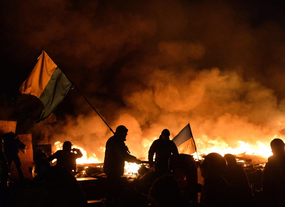 EuroMaidan protesters hold Ukrainian flags as they clash with riot police on Independence Square in Kyiv on Feb. 19, 2014. A day later, riot police open fire on protesters killing around 100 people. The EuroMaidan Revolution ended after pro-Kremlin President Viktor Yanukovych fled the country. (Getty Images)