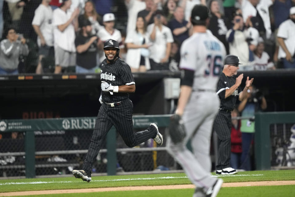 Chicago White Sox's Elvis Andrus smiles as he scores on Luis Robert Jr.'s single off Miami Marlins relief pitcher Dylan Floro, right, duirng the ninth inning of a baseball game Friday, June 9, 2023, in Chicago. (AP Photo/Charles Rex Arbogast)