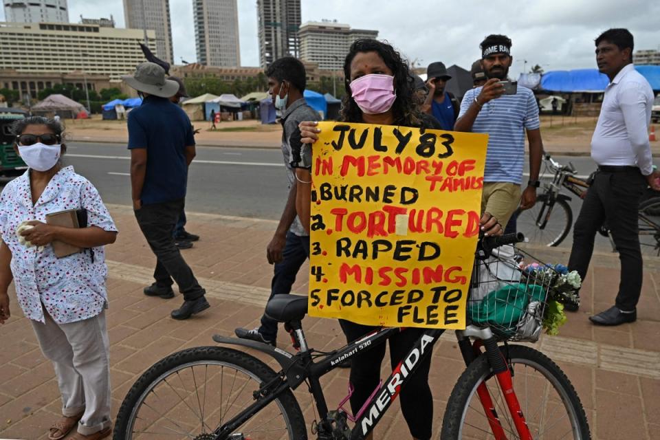 A demonstrator holds a placard during a protest to observe the anniversary of anti-Tamil rioting (AFP via Getty Images)