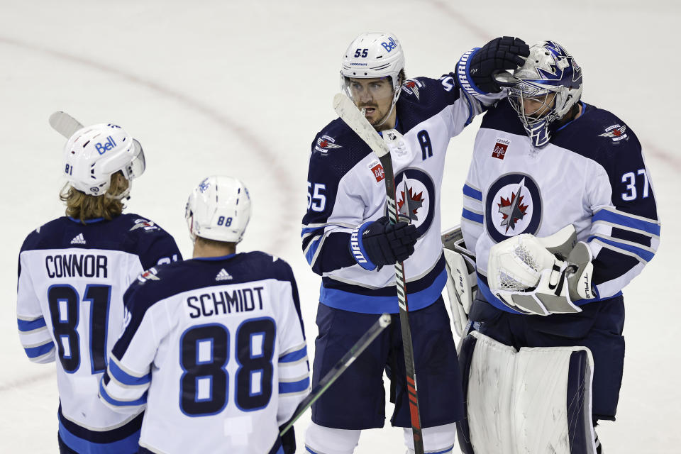 Winnipeg Jets center Mark Scheifele (55) celebrates with goaltender Connor Hellebuyck after the third period of an NHL hockey game against the New York Rangers on Monday, Feb. 20, 2023, in New York. The Jets won 4-1. (AP Photo/Adam Hunger)