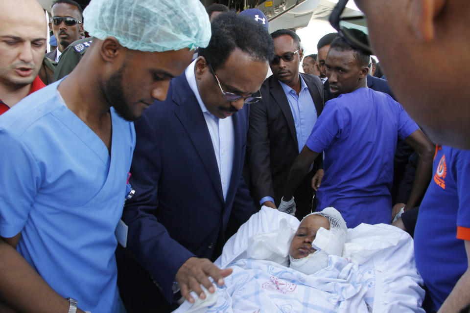 Somalia's President Mohamed Abdullahi Mohamed reacts with a wounded person to be airlifted to the Turkish capital for treatment after being injured in Saturday's car bomb blast in Mogadishu, Somalia, Sunday, Dec. 29, 2019. A truck bomb exploded at a busy security checkpoint in Somalia's capital Saturday morning, killing at least 79 people including many students, authorities said. It was the worst attack in Mogadishu since the devastating 2017 bombing that killed hundreds. (AP Photo/Farah Abdi Warsameh)