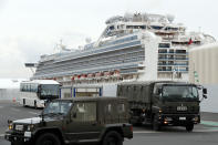 A bus carrying the passengers from the quarantined Diamond Princess cruise ship escorted by Japan Self Defense Forces vehicles leaving a port in Yokohama, near Tokyo, Thursday, Feb. 20, 2020. Passengers tested negative for COVID-19 started disembarking since Wednesday. (AP Photo/Eugene Hoshiko)