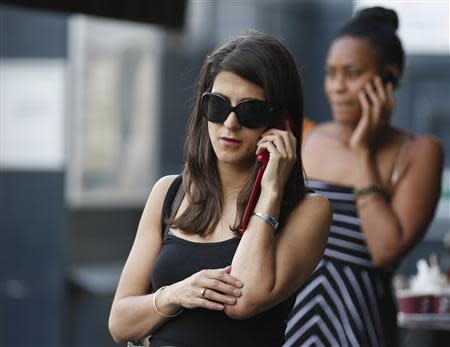 Women use their mobile phones in central London August 30, 2013. Verizon is close to buying the 45 percent stake in the joint venture Verizon Wireless from Vodafone, according to sources. REUTERS/Olivia Harris