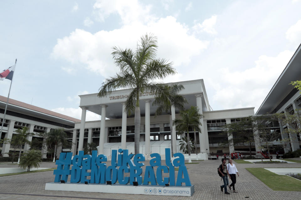 A couple walk past a sculpture of a hashtag that reads in Spanish: "Give democracy a like", outside the Electoral Tribunal headquarters in Panama City, Thursday, May 2, 2019. In what has been perhaps the shortest and least colorful campaign since Panama's transition to democracy three decades ago, most election talk has focused on governmental malfeasance following the massive leak of law firm documents in the Panama Papers. (AP Photo/Arnulfo Franco)