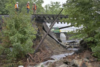 Workers survey the damage to a Commuter Rail train line which was washed out Tuesday, Sept. 12, 2023, in Leominster, Mass. after heavy rain fall in the town overnight. (AP Photo/Josh Reynolds)