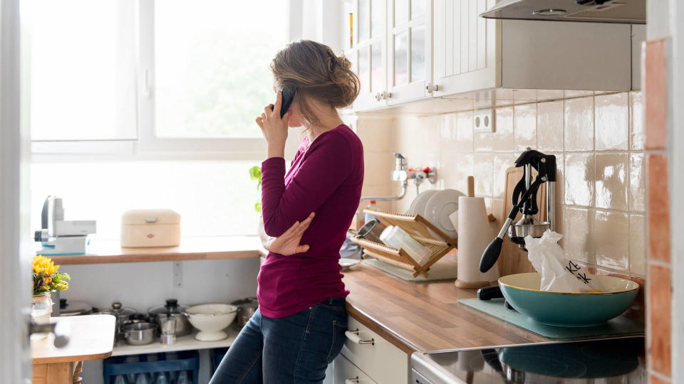 A young woman is at home in her apartment making a phone call.