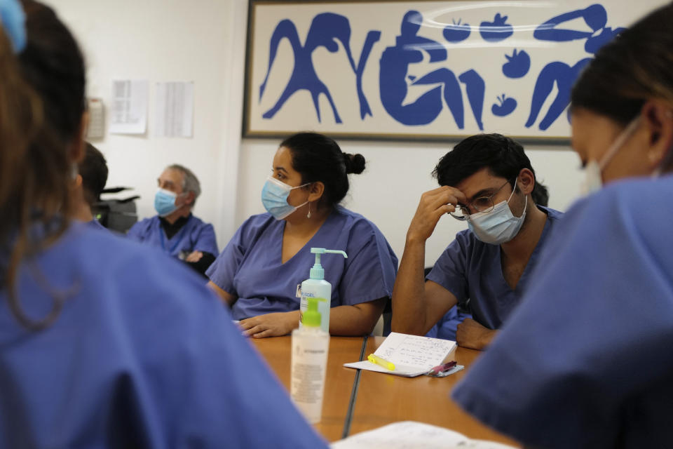 Medical staff, including Dr. Philippe Montravers, second left in background, attend a morning meeting, at Bichat Hospital, AP-HP, in Paris Tuesday, Dec. 1, 2020. Even for hospital staff for whom death is a constant, witnessing the loss of a fellow human being to COVID-19 is a churn of emotions. At the Paris hospital that recorded the first virus death outside Asia, nurses and paramedics in the intensive care unit have their own coping mechanisms.(AP Photo/Francois Mori)