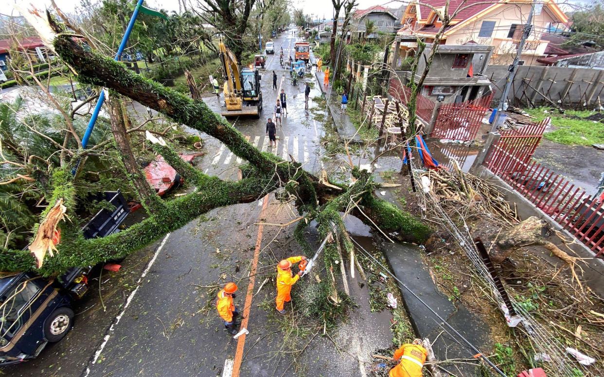 Filipino government workers clear a toppled tree in the typhoon-hit town of Tigaon, Camarines Sur, Philippines - FRANCIS R MALASIG/EPA-EFE/Shutterstock