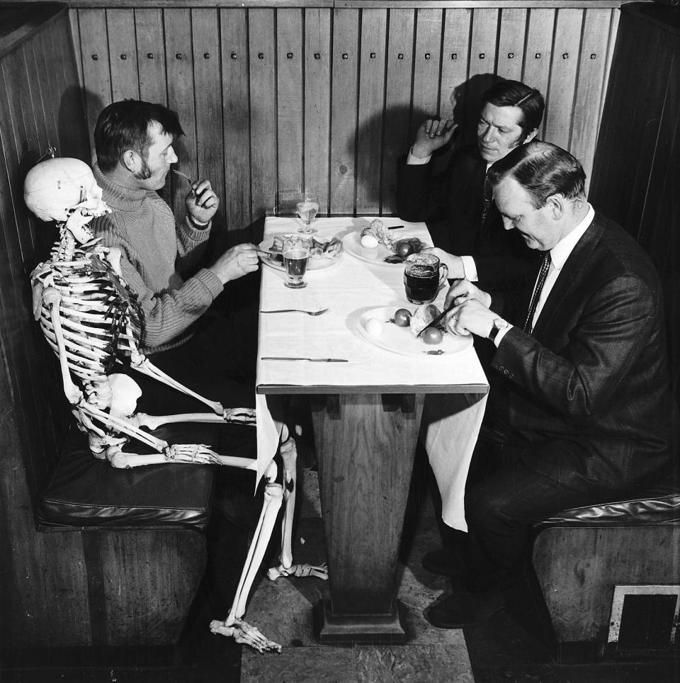 A skeleton sits at pub table waiting to be served. 26th May 1970.