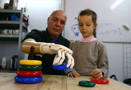 Sergey Galtsev builds a children's pyramid with his granddaughter Anna while testing a prosthetic right hand, made by his son Oleg, in Minsk, Belarus October 16, 2016. REUTERS/Vasily Fedosenko