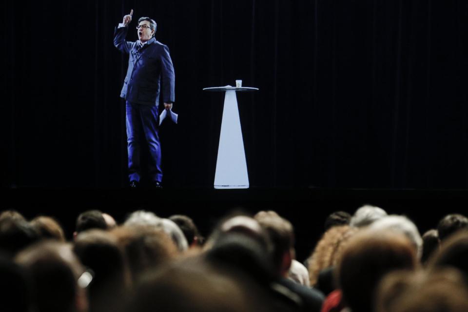 The hologram of hard-left French presidential candidate Jean-Luc Melenchon speaks to supporters who are gathered in Saint-Denis, near Paris, Sunday, Feb. 5, 2017. As Melenchon holds a rally in Lyon Sunday, a hologram of him is being projected by satellite to crowds in Paris. (AP Photo/Kamil Zihnioglu)