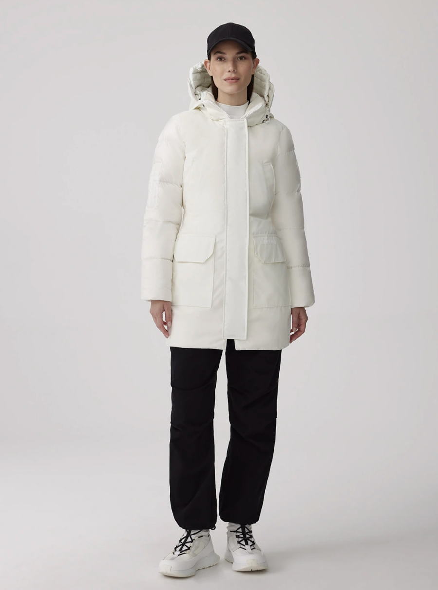 model wearing white boots, black pants and white canada goose jacket, Paradigm Trillium Parka in North Star White (Photo via Canada Goose)