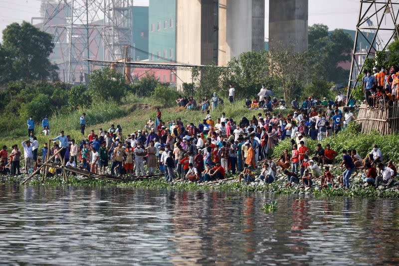 Relatives and onlookers look on after several people died when a ferry collided with a cargo vessel and sank on Sunday in the Shitalakhsyaa River in Narayanganj