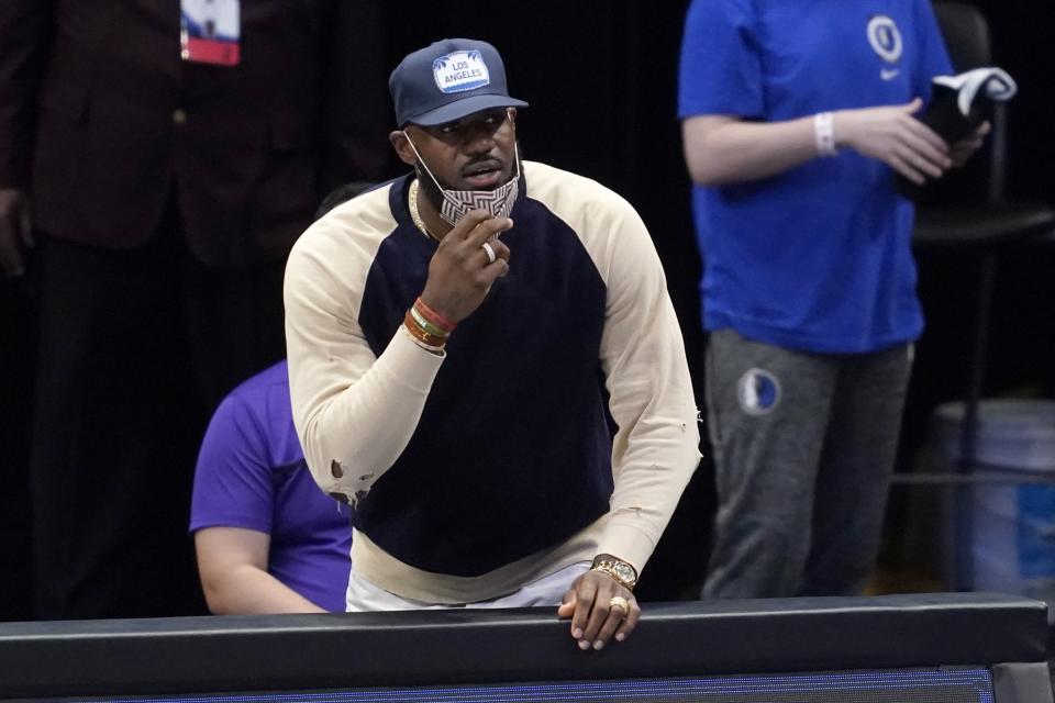 Los Angeles Lakers forward LeBron James watches from the bench as the team plays the Dallas Mavericks in the first half of an NBA basketball game in Dallas, Thursday, April 22, 2021. (AP Photo/Tony Gutierrez)