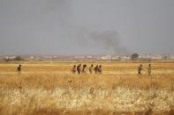 Rebel fighters in Marea city walk near rising smoke after strikes on Syria Democratic Forces (SDF) controlled Tell Rifaat town, northern Aleppo province, Syria October 21, 2016. REUTERS/Khalil Ashawi