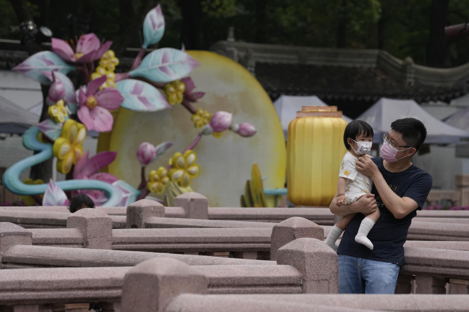 A man and child wearing masks visit Yu Garden Mall, Thursday, June 2, 2022, in Shanghai. Traffic, pedestrians and joggers reappeared on the streets of Shanghai on Wednesday as China's largest city began returning to normalcy amid the easing of a strict two-month COVID-19 lockdown that has drawn unusual protests over its heavy-handed implementation. (AP Photo/Ng Han Guan)