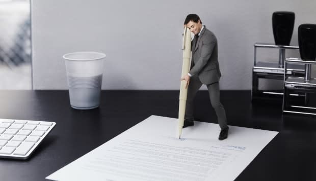 Small businessman signing document on office desk