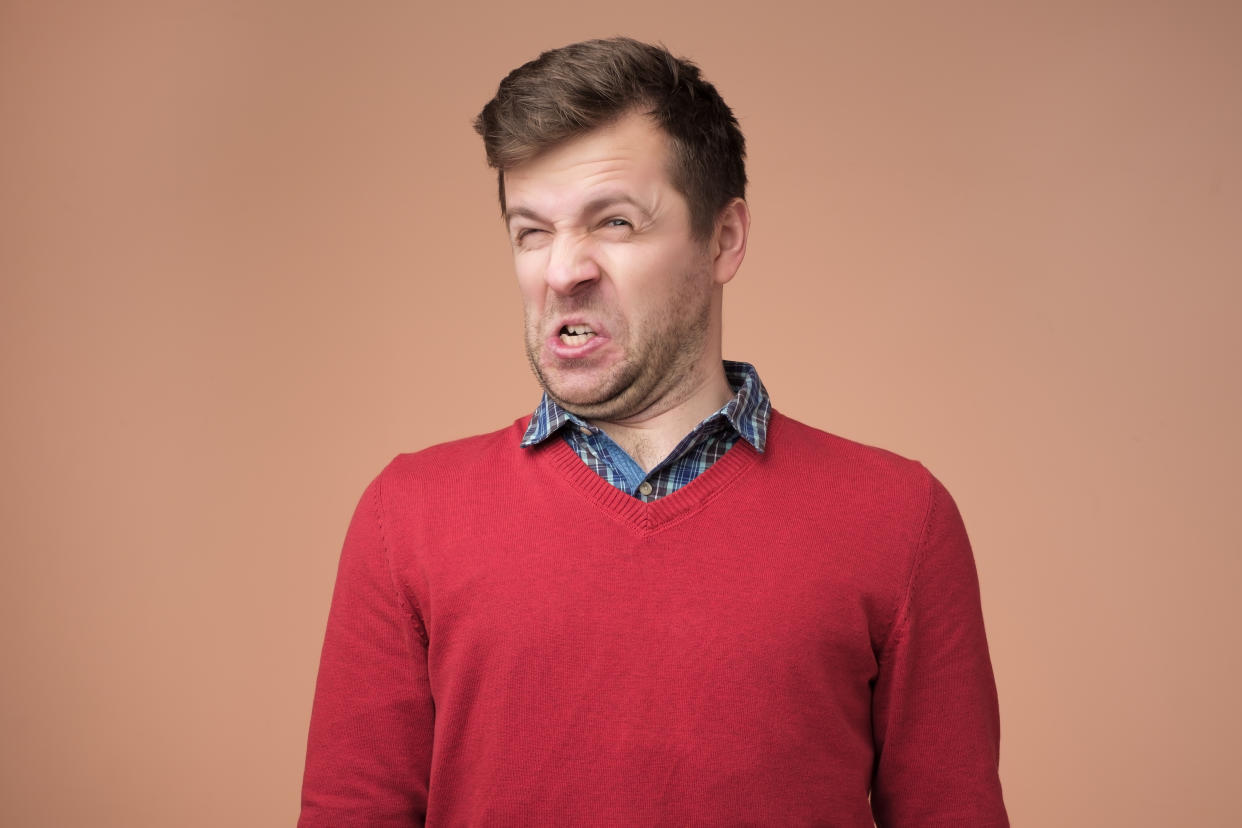 Disguting smell concept. Shocked young man looking at something unpleasant and bad, isolated on gray background. Negative emotion concept