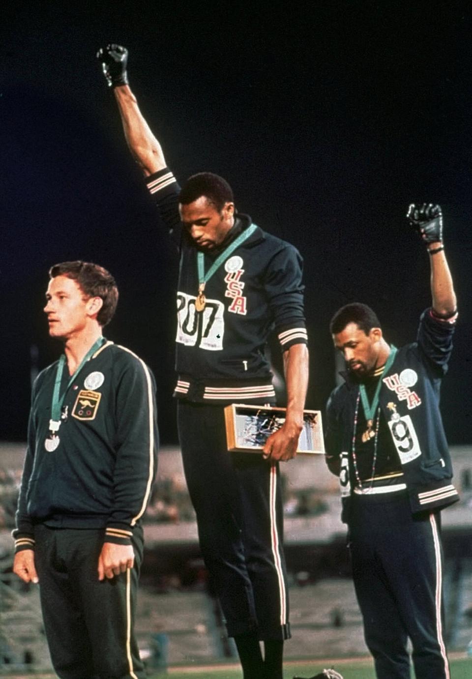 FILE - In this Oct. 16, 1968, file photo, extending gloved hands skyward in racial protest, U.S. athletes Tommie Smith, center, and John Carlos stare downward during the playing of national anthem after Smith received the gold and Carlos the bronze for the 200 meter run at the Summer Olympic Games in Mexico City. Australian silver medalist Peter Norman is at left. The U.S. Olympic and Paralympic Committee is signaling willingness to challenge longstanding IOC rules restricting protests at the Olympics, while also facing backlash from some of its own athletes for moves viewed by some as not being driven by sufficient athlete input. (AP Photo/File)