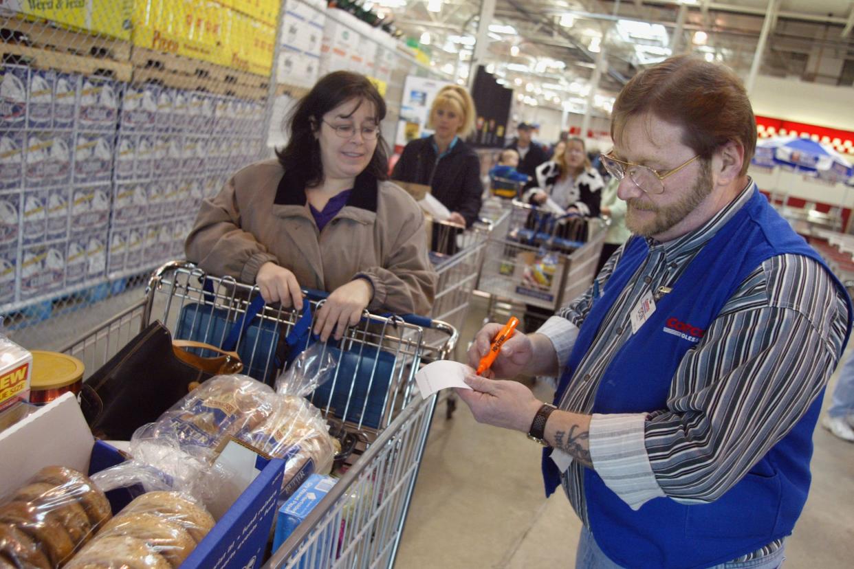 sales associate Don Ebert (R) checks a shopper's purchase March 8, 2002 at a Costco Wholesale store in Niles, Illinois