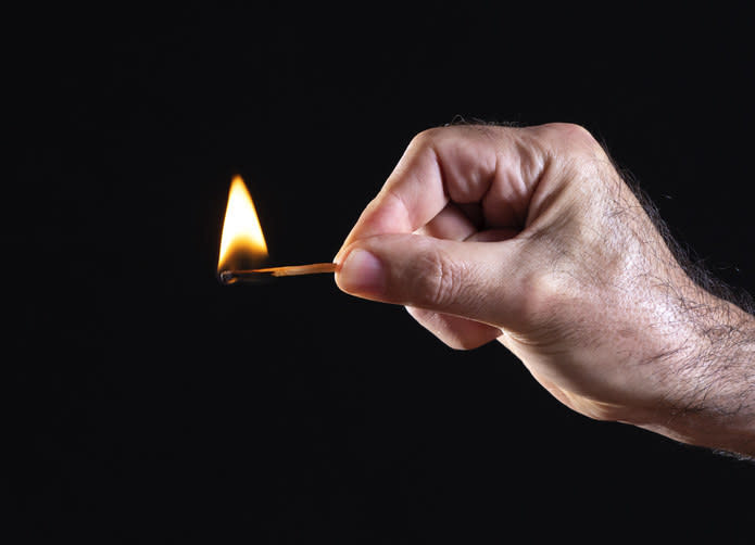 A man's hand holding a match