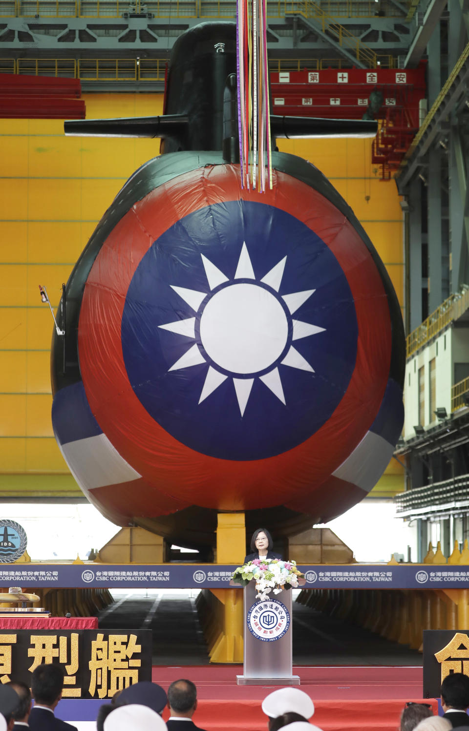 Taiwan's President Tsai Ing-wen, standing in front of a covered submarine, delivers a speech during the naming and launching ceremony of domestically-made submarines at CSBC Corp's shipyards in Kaohsiung, Southern Taiwan, Thursday, Sept. 28, 2023. The submarine, if successful in its tests, will be a major breakthrough for Taiwan in shipbuilding and design. (AP Photo/Chiang Ying-ying)