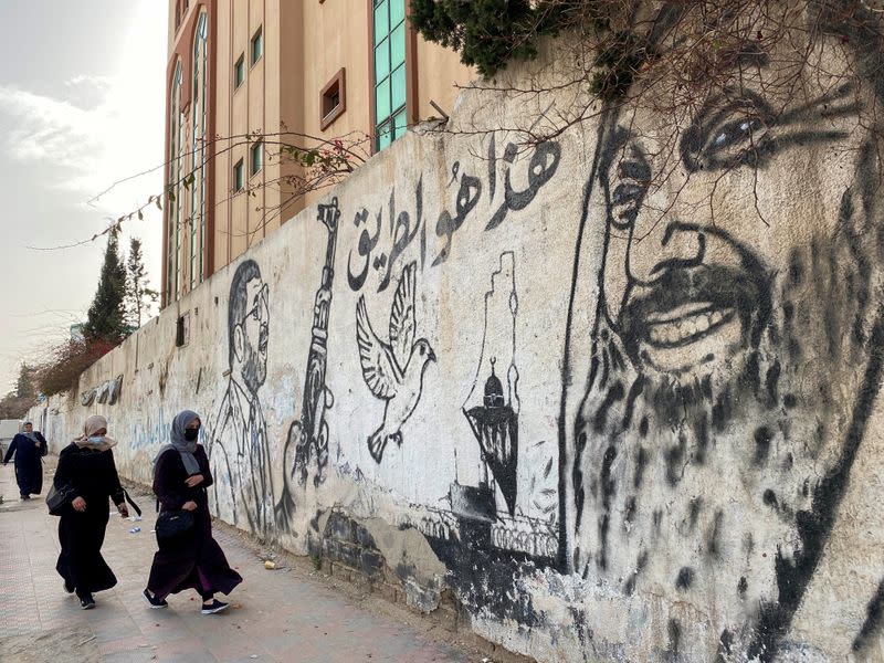 Palestinian women walk past a mural depicting late Hamas leaders Ahmed Yassin and Abdel-Aziz Al-Rantissi, in Gaza City