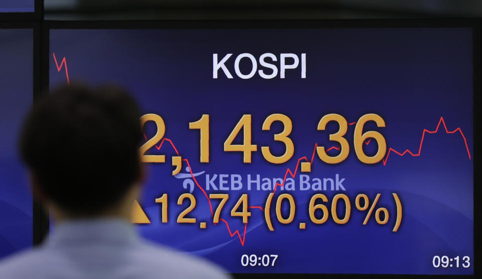 A currency trader walks by the screen showing the Korea Composite Stock Price Index (KOSPI) at the foreign exchange dealing room in Seoul, South Korea, Monday, July 1, 2019. Asian markets took heart Monday from revived hopes for progress in trade negotiations between the U.S. and China after President Donald Trump met with China's Xi Jinping at the Group of 20 summit in Japan. (AP Photo/Lee Jin-man)
