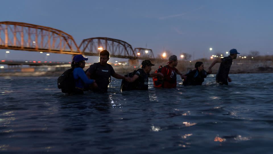 Migrants link arms with each other as they wade into the Rio Grande River with intentions to cross into Eagle Pass, Texas, on February 24. - Cheney Orr/Reuters