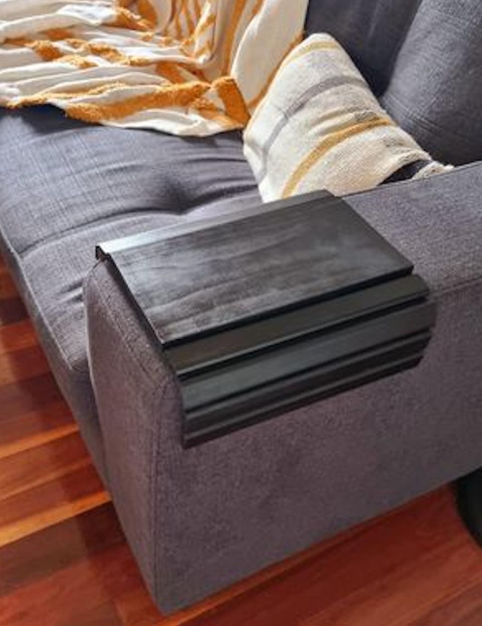 A grey fabric lounge on a wooden floor has a darker grey fabric cover over one arm to protect it.